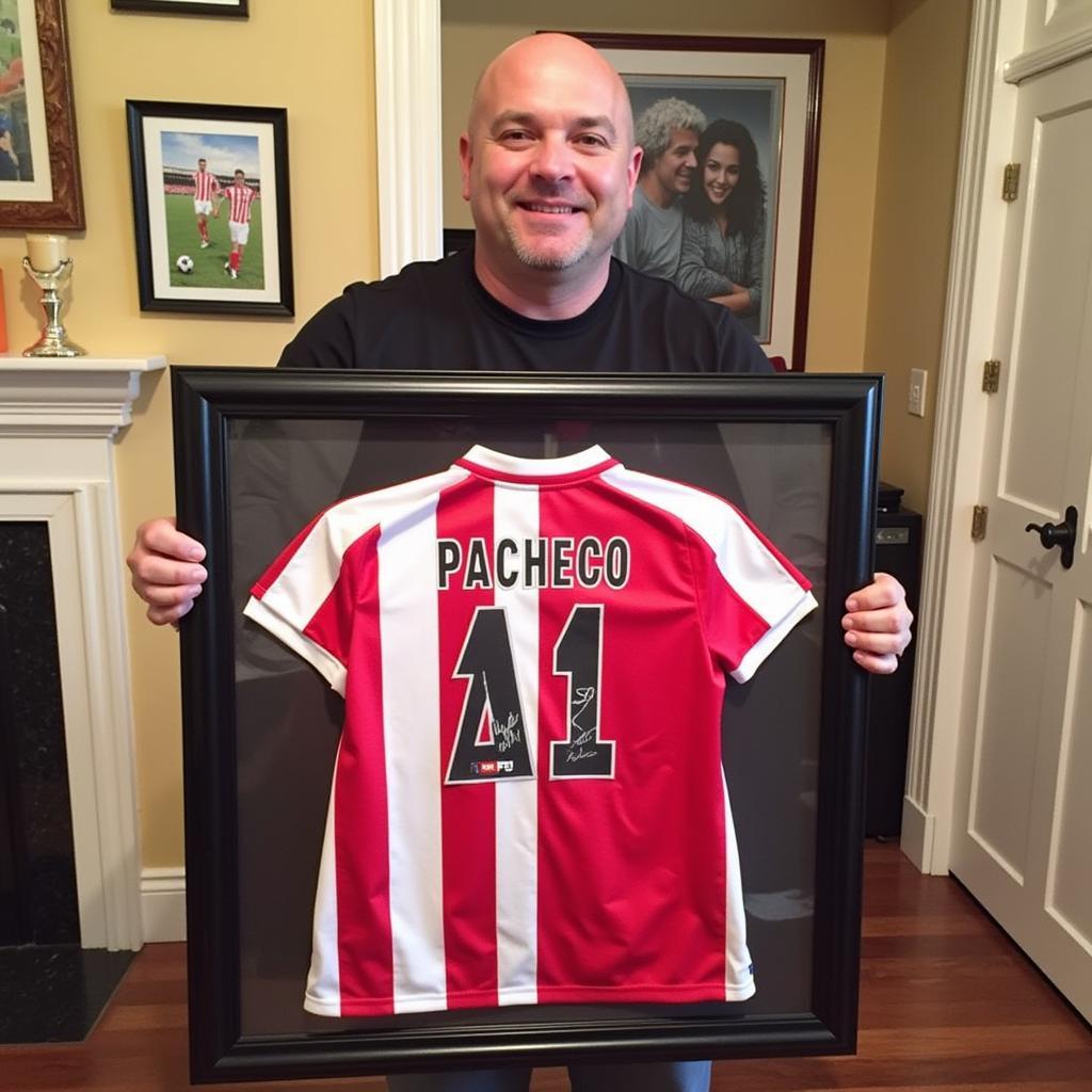 De Jong holding up a framed Pacheco jersey with a proud smile.