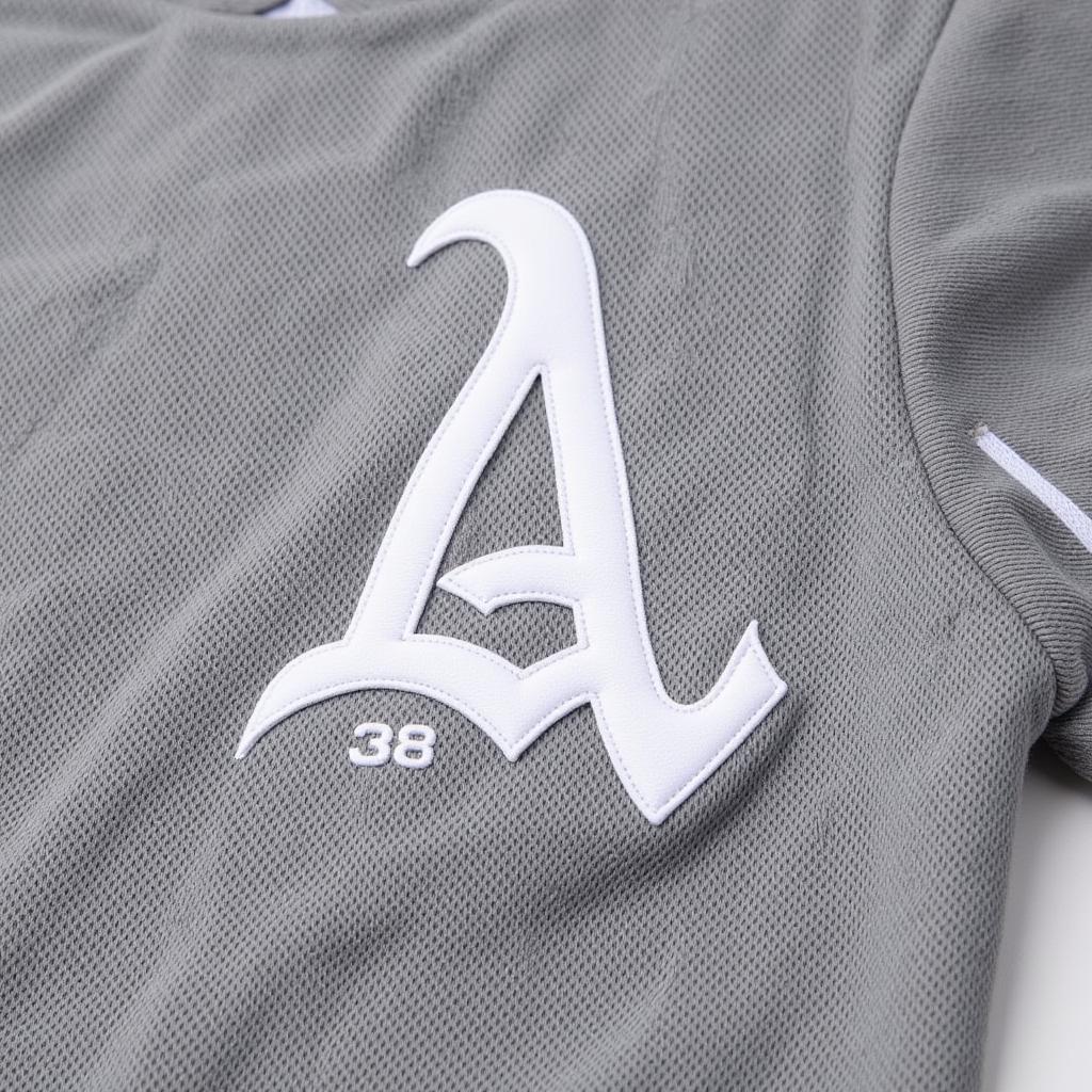 Close-up view of the stitching and fabric of a grey and white baseball jersey